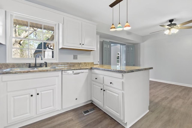 kitchen with visible vents, wood finished floors, a peninsula, white dishwasher, and a sink