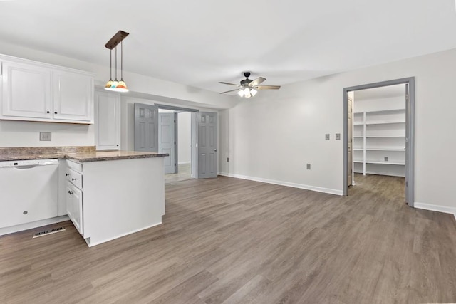 kitchen with white dishwasher, light wood-style flooring, a peninsula, white cabinetry, and baseboards