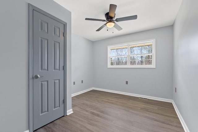 spare room featuring visible vents, baseboards, ceiling fan, and wood finished floors