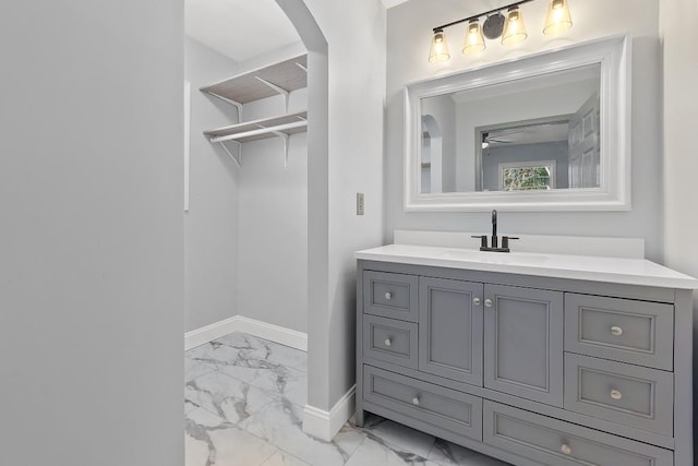 bathroom featuring marble finish floor, a ceiling fan, vanity, and baseboards