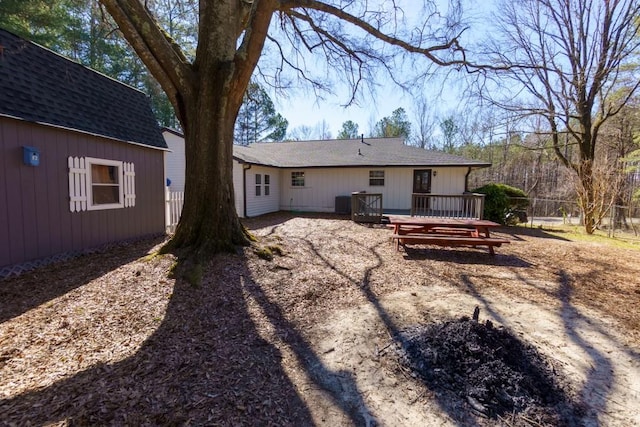 rear view of house with a deck and roof with shingles