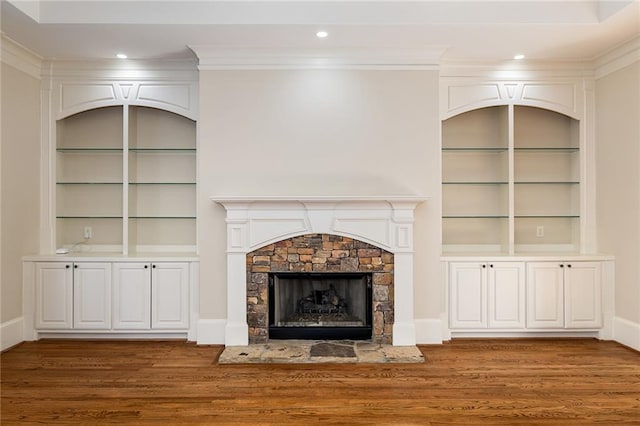 unfurnished living room with a fireplace, built in features, dark hardwood / wood-style floors, and ornamental molding