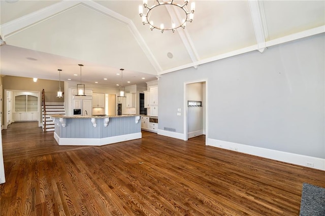 kitchen featuring paneled fridge, a large island with sink, dark hardwood / wood-style floors, white cabinetry, and hanging light fixtures