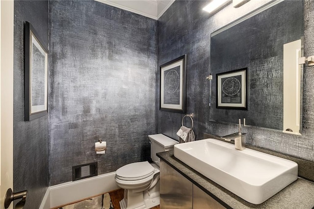 bathroom with vanity, toilet, and ornamental molding