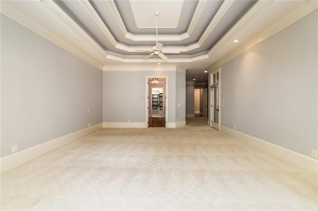 carpeted empty room featuring ceiling fan, a raised ceiling, and crown molding