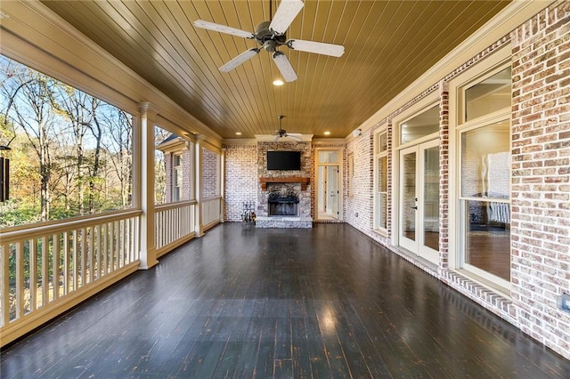 unfurnished sunroom with an outdoor stone fireplace, ceiling fan, and wood ceiling