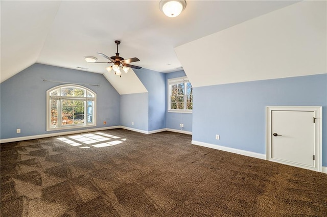 bonus room featuring dark colored carpet, a healthy amount of sunlight, and vaulted ceiling