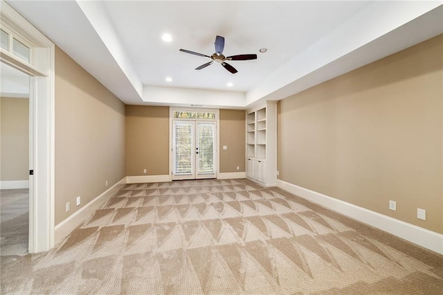 interior space with ceiling fan, light colored carpet, french doors, and a tray ceiling