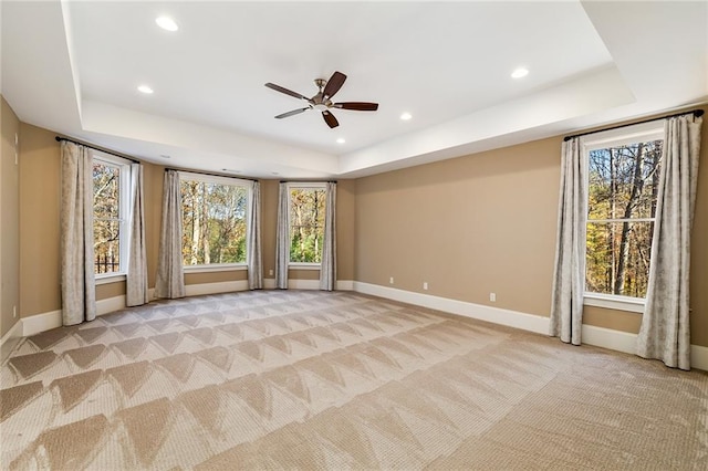 unfurnished living room featuring a raised ceiling, ceiling fan, and light colored carpet