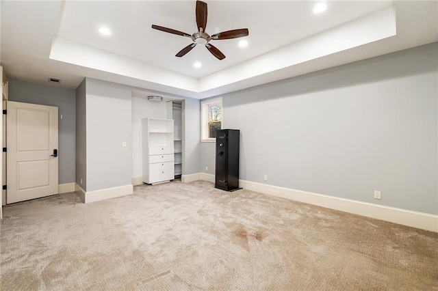 unfurnished bedroom featuring light colored carpet, a raised ceiling, and ceiling fan