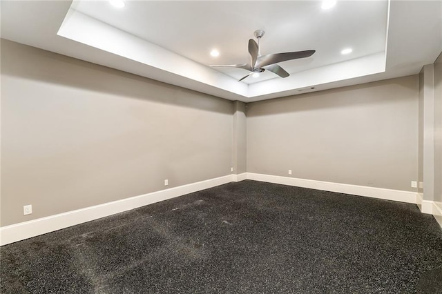 carpeted spare room featuring a tray ceiling and ceiling fan