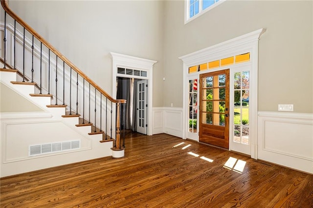 entrance foyer with plenty of natural light, a towering ceiling, dark wood-type flooring, and french doors