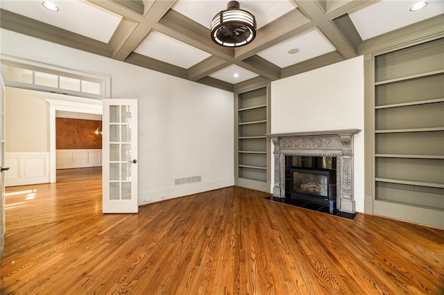 unfurnished living room with hardwood / wood-style floors, french doors, coffered ceiling, built in features, and beamed ceiling