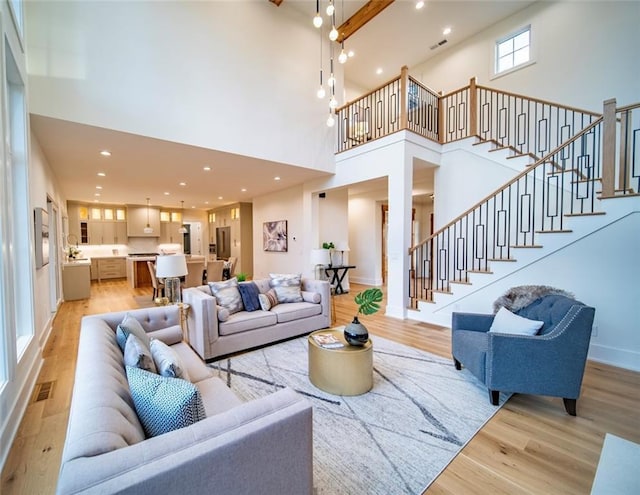 living room featuring stairway, recessed lighting, light wood-type flooring, and a towering ceiling