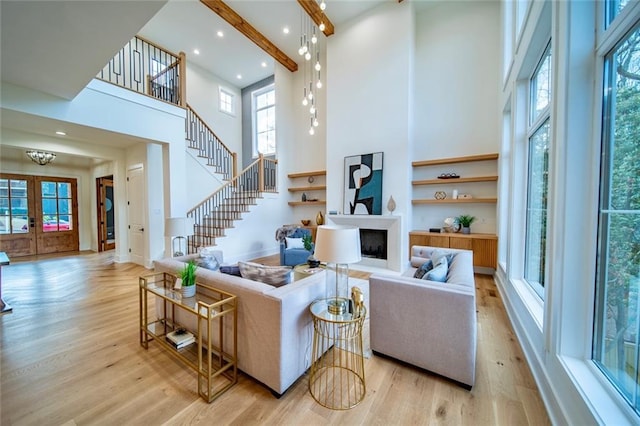 living area with stairs, a fireplace, wood finished floors, and a towering ceiling