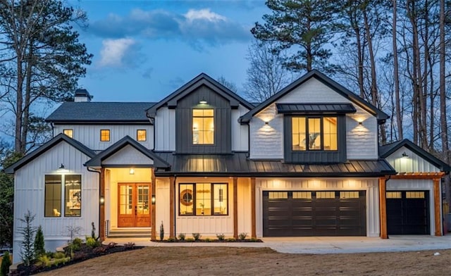 modern farmhouse style home with concrete driveway, a chimney, metal roof, a garage, and a standing seam roof