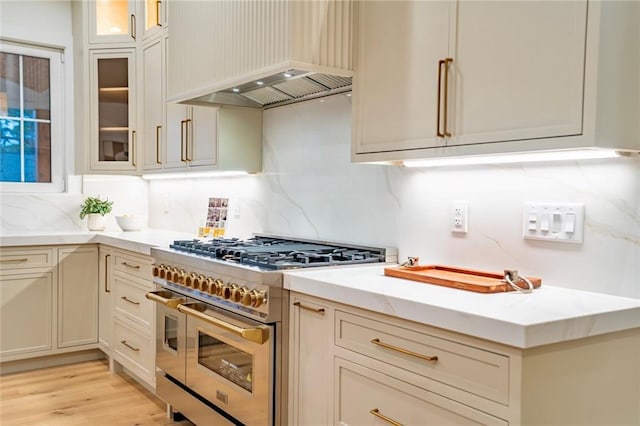 kitchen featuring double oven range, glass insert cabinets, tasteful backsplash, and custom range hood