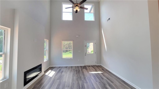 5110 Black Bear Trl, Douglasville, GA 30135 - unfurnished living room with a towering ceiling, wood finished floors, a ceiling fan, baseboards, and a glass covered fireplace