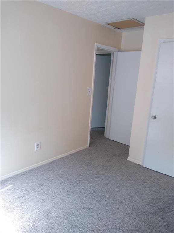 carpeted spare room with baseboards and attic access