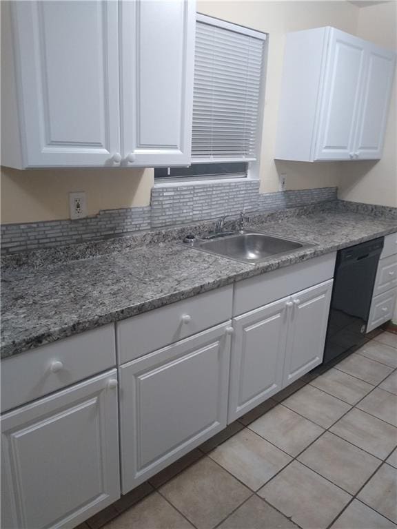 kitchen with a sink, black dishwasher, light tile patterned flooring, and white cabinetry