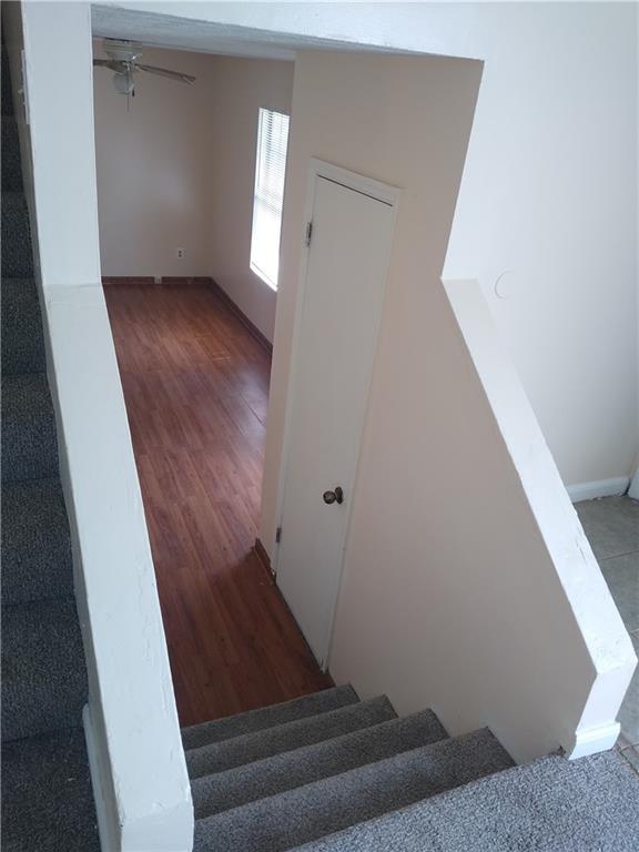 stairway with a ceiling fan and wood finished floors