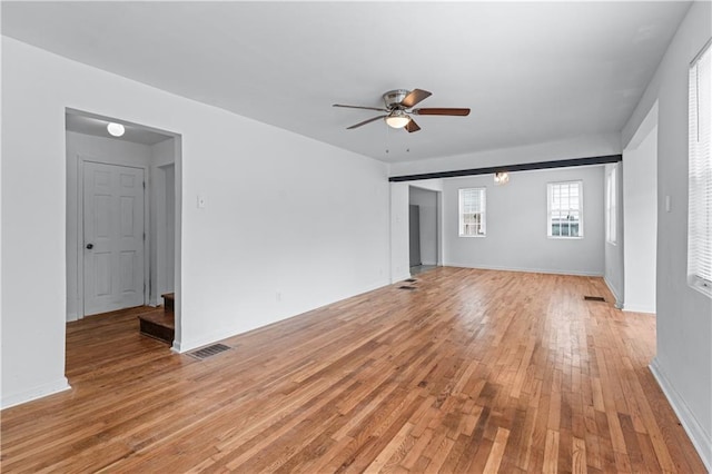 unfurnished living room featuring light wood-type flooring, a ceiling fan, baseboards, and visible vents