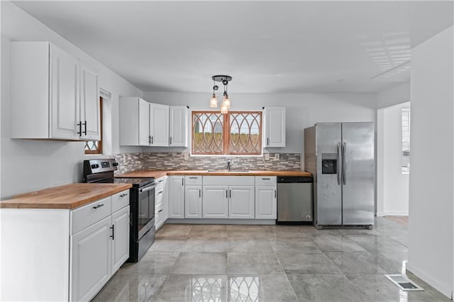 kitchen with appliances with stainless steel finishes, butcher block counters, and a wealth of natural light