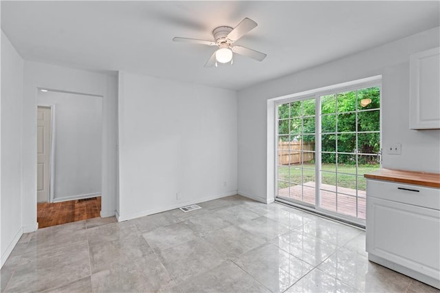 spare room with baseboards, ceiling fan, and visible vents