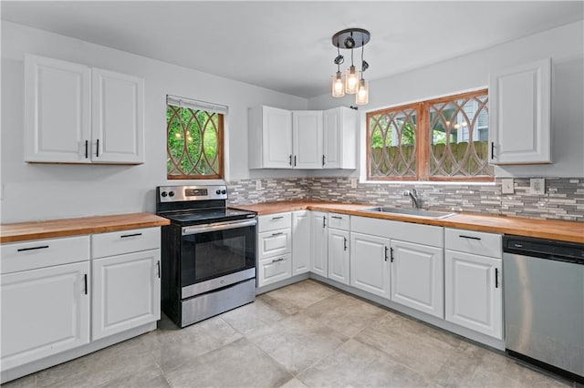 kitchen with a sink, appliances with stainless steel finishes, decorative backsplash, and butcher block countertops