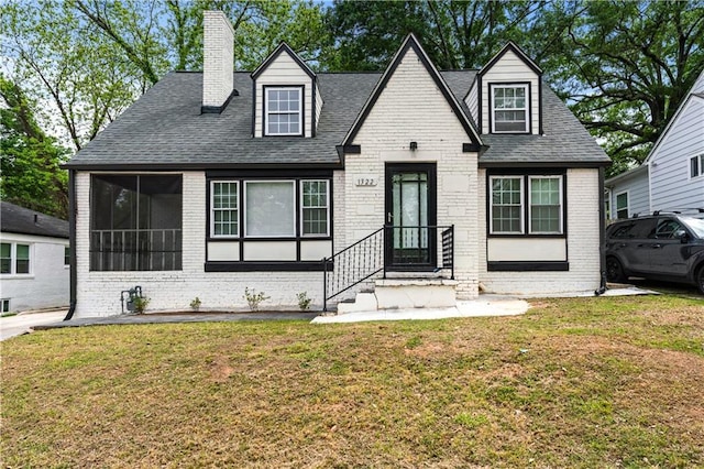 new england style home with brick siding and a front lawn
