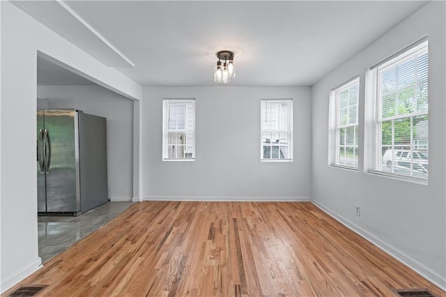 unfurnished dining area with baseboards, wood finished floors, and visible vents