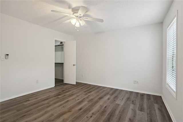 unfurnished bedroom with ceiling fan, a closet, dark hardwood / wood-style flooring, and multiple windows