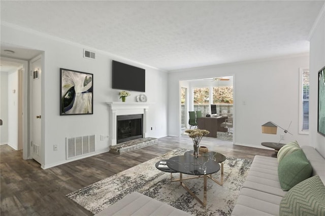 living room with dark hardwood / wood-style flooring, crown molding, a textured ceiling, and a healthy amount of sunlight