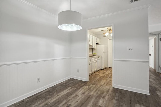 unfurnished dining area with dark wood-type flooring, ceiling fan, and ornamental molding