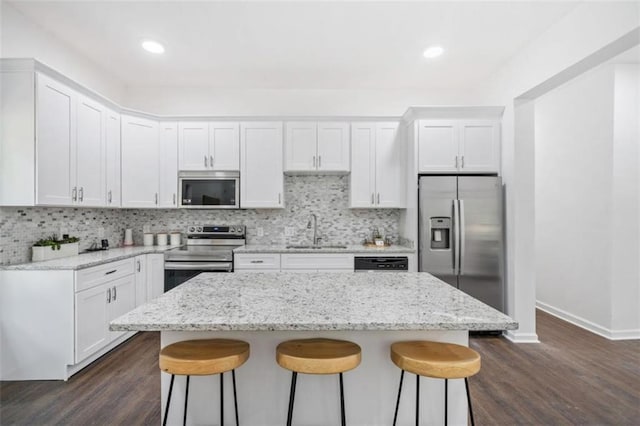 kitchen featuring decorative backsplash, a kitchen breakfast bar, appliances with stainless steel finishes, and a sink