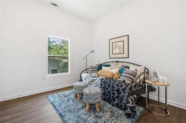 bedroom with visible vents, baseboards, and wood finished floors