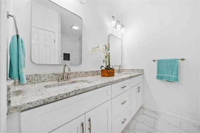 full bathroom featuring baseboards, a marble finish shower, double vanity, a sink, and marble finish floor