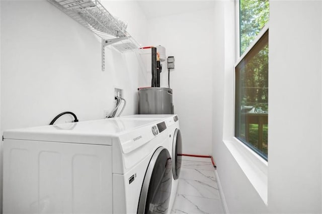 laundry area featuring washing machine and clothes dryer, baseboards, water heater, laundry area, and marble finish floor