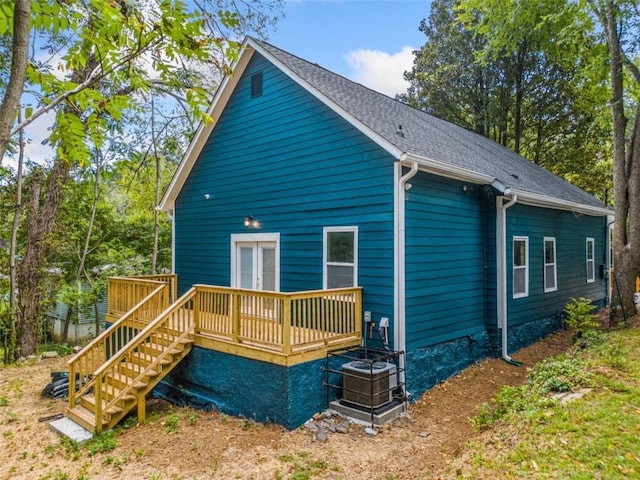 back of property featuring a deck, stairs, and a shingled roof