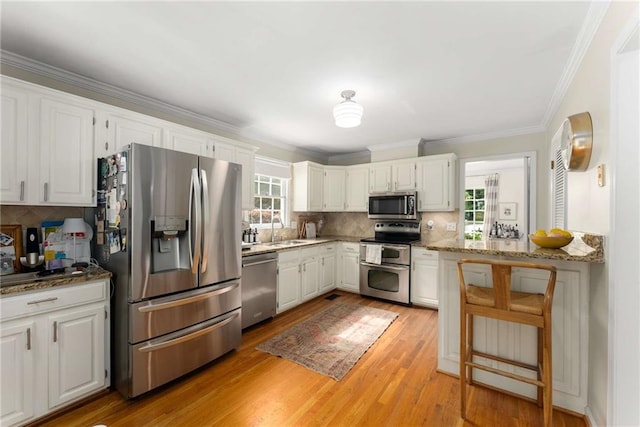 999 Seaboard Ave NW, Atlanta, GA 30318 - kitchen featuring stainless steel appliances, plenty of natural light, ornamental molding, tasteful backsplash, and white cabinetry