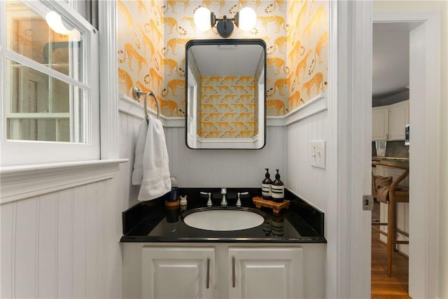 999 Seaboard Ave NW, Atlanta, GA 30318 - bathroom featuring wainscoting, wood finished floors, vanity, wallpapered walls, and a decorative wall