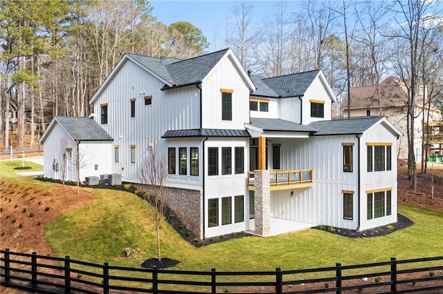 rear view of house featuring a balcony, central AC unit, a lawn, and a sunroom