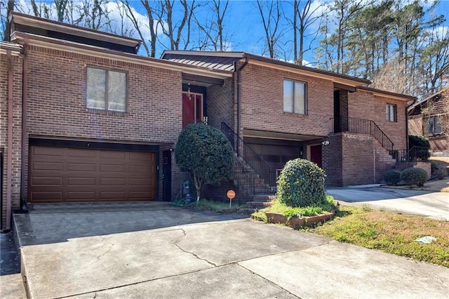 view of front of house featuring a garage, brick siding, concrete driveway, and stairs