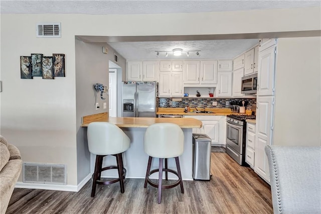 kitchen featuring a kitchen bar, light countertops, visible vents, and stainless steel appliances