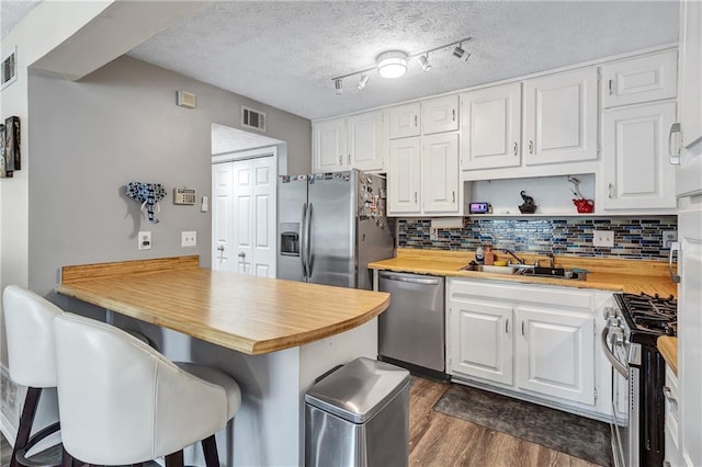 kitchen featuring a sink, a peninsula, visible vents, and stainless steel appliances