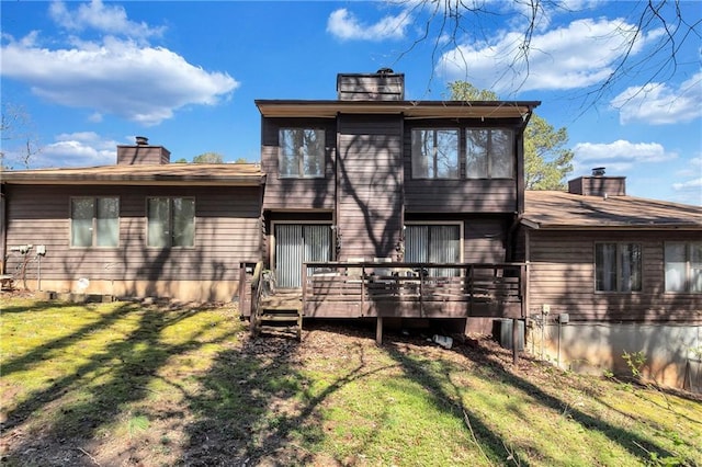 rear view of house featuring a deck, a lawn, and a chimney