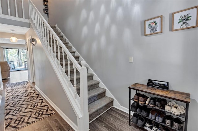 staircase featuring wood finished floors and baseboards