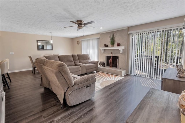 living area with a wealth of natural light, a textured ceiling, dark wood-type flooring, and baseboards