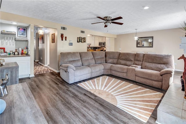 living area featuring dark wood-type flooring, visible vents, and a textured ceiling