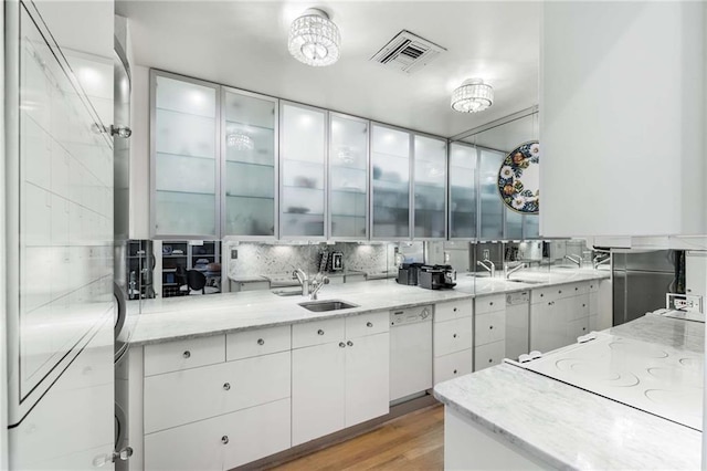 kitchen with sink, light stone counters, light wood-type flooring, white appliances, and white cabinets